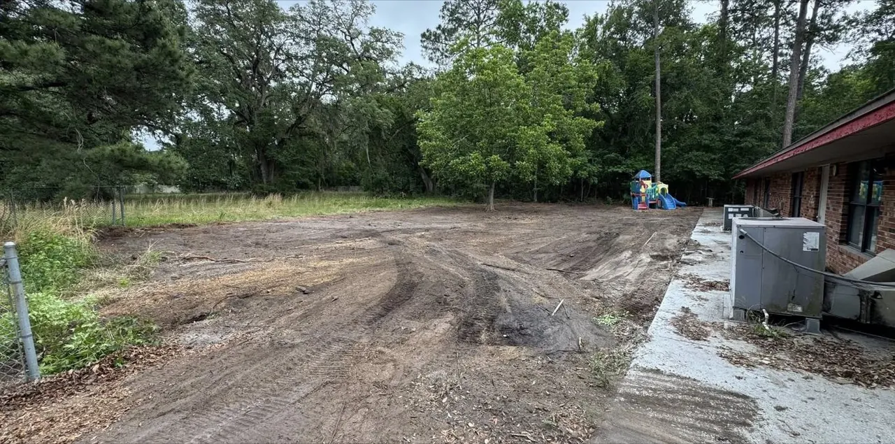 Cleared dirt yard where the playground stood, beside the brick building