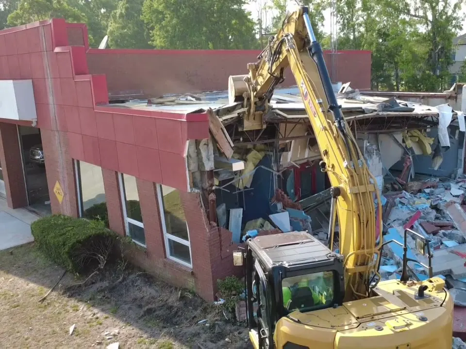 Excavator opening up a wing of Kingsland Fire Station #3 while the rest of the building stands